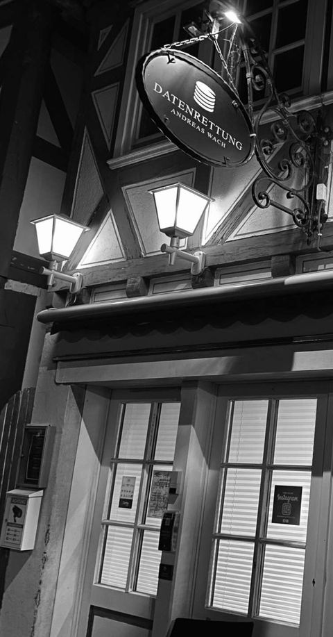 Beleuchtete Außenansicht des Geschäfts von Datenrettung Andreas Wach mit der Aufschrift 'Digitale Schätze' in einer dunklen Umgebung.