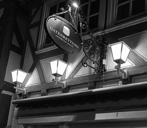 Beleuchtete Außenansicht des Geschäfts von Datenrettung Andreas Wach mit der Aufschrift 'Digitale Schätze' in einer dunklen Umgebung.