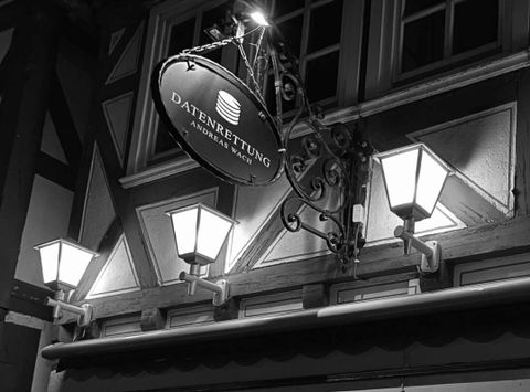 Beleuchtete Außenansicht des Geschäfts von Datenrettung Andreas Wach mit der Aufschrift 'Digitale Schätze' in einer dunklen Umgebung.