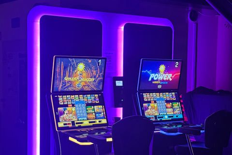 Zwei Spielautomaten in einem dunklen Raum mit lila Beleuchtung - Happy Billard