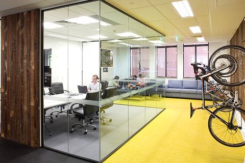 Realisierte Arbeitswelt bei Atlassian: Team-Bereich mit verglastem Meetingraum und individuellen Gestaltungselementen, als Workplace Strategin entwickelt und geplant