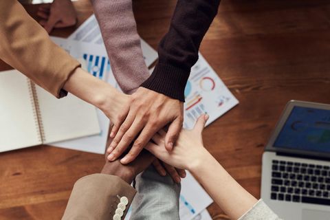 Mehrere Hände, die sich zusammentun, um Teamarbeit und Zusammenhalt zu symbolisieren. - Coaching Komplizin