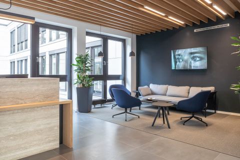 Realisierte Arbeitswelt bei Santen: Empfangsbereich mit warmen Materialkontrasten und ruhiger Lounge-Atmosphäre, als Workplace Strategin entwickelt und geplant
