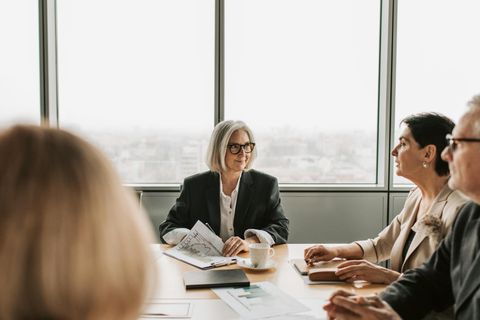 Geschäftsleute in einem Konferenzraum, die an einem Tisch sitzen und diskutieren - Coaching Komplizin
