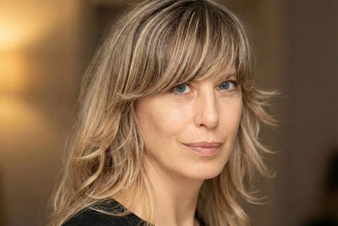 Porträt einer blonden Frau mit welligen Haaren und blauen Augen, die in die Kamera blickt - Alexandra Lier