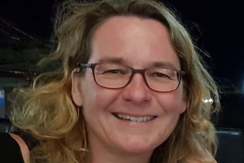 Eine lächelnde Frau mit lockigem Haar und Brille - Coaching Komplizin