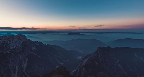 Atemberaubende Berglandschaft bei Sonnenuntergang mit Blick auf die nebligen Täler und Berggipfel am Horizont. - Mut Mach Lehre