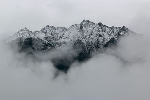 Verschneite Bergspitzen, die in Nebel und Wolken gehüllt sind - Mut Mach Lehre